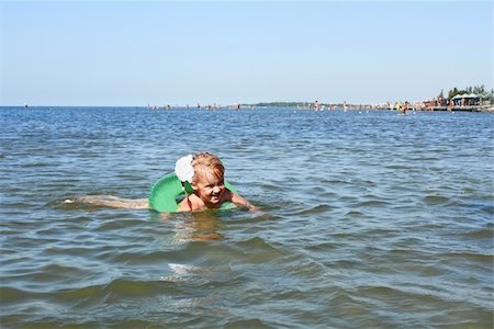 Little girl swimming on inflatable wheel against crowded beach Stock Photo - Budget Royalty-Free & Subscription, Code: 400-06388208