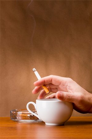 Hand holding a cigarette and a cup ashtray. Stock Photo - Budget Royalty-Free & Subscription, Code: 400-06389888