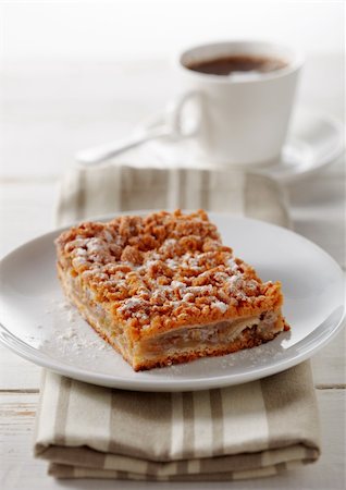 simsearch:400-06946823,k - Close-up of a pie on a plate with a napkin and a cup with tea at the back. Fotografie stock - Microstock e Abbonamento, Codice: 400-06395815