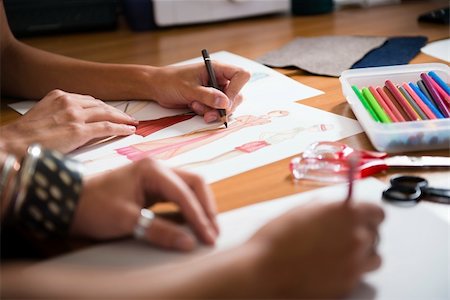 two young women working as fashion designers and drawing sketches for clothes in atelier. Cropped view Stock Photo - Budget Royalty-Free & Subscription, Code: 400-06395932