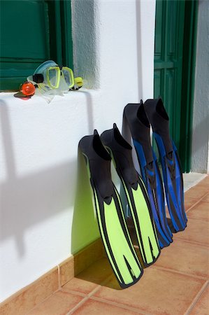 Schnorchelausrüstung (blaue Flossen, gelbe Schnorchel und transparente Maske) platziert vor dem Gebäude. Kanarische Inseln, Lanzarote. Stockbilder - Microstock & Abonnement, Bildnummer: 400-06396816