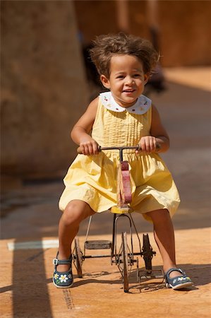 Happy girl riding a centenarian toy tricycle Stock Photo - Budget Royalty-Free & Subscription, Code: 400-06391384