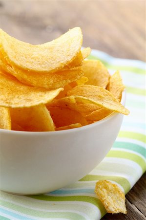 paper thin - potato chips in a white bowl on a wooden table Foto de stock - Super Valor sin royalties y Suscripción, Código: 400-06393368