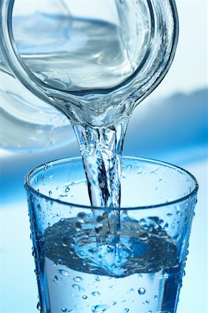 simsearch:400-04823336,k - Water pouring from a jug into a glass on blue. Fotografie stock - Microstock e Abbonamento, Codice: 400-06415759