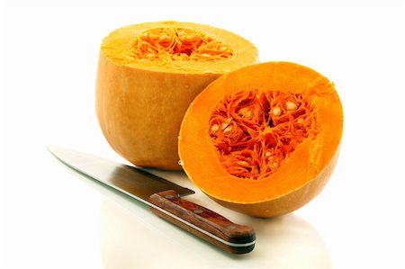 semilla de calabaza - Two halves of a ripe pumpkin and a table knife on a white background. Foto de stock - Super Valor sin royalties y Suscripción, Código: 400-06416284