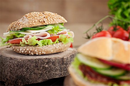 Delicious ham, cheese and salami sandwich with vegetables, lettuce, cherry tomatoes in natural setting with wooden background Stock Photo - Budget Royalty-Free & Subscription, Code: 400-06418663