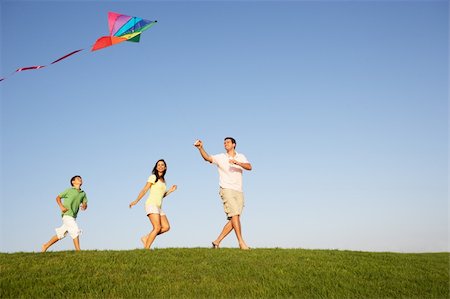 side view of man flying kites - Young family, parents with child, playing in a field Stock Photo - Budget Royalty-Free & Subscription, Code: 400-06419404