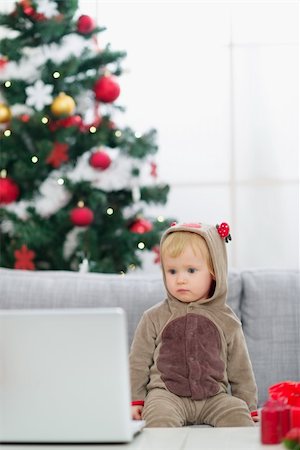 simsearch:400-06419734,k - Baby in Christmas deer costume near Christmas tree looking in laptop Stock Photo - Budget Royalty-Free & Subscription, Code: 400-06419764