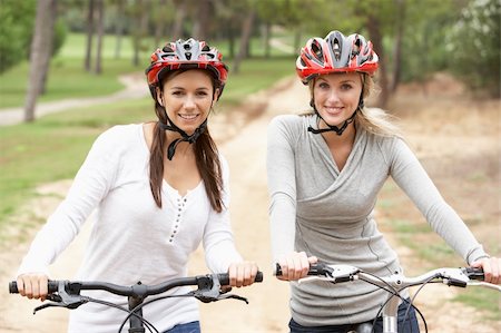 simsearch:6128-08738600,k - Two Female friends riding bikes in park Stock Photo - Budget Royalty-Free & Subscription, Code: 400-06420418