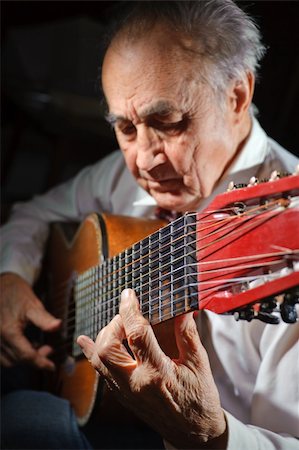 simsearch:400-04065514,k - An elderly man in white shirt playing an acoustic guitar. Dark background. Focus on the hand. Foto de stock - Super Valor sin royalties y Suscripción, Código: 400-06420760