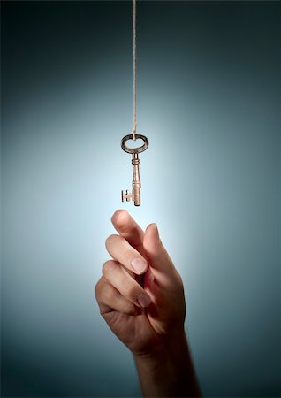 Conceptual image of a hand taking an old key hanging from a string. Stock Photo - Budget Royalty-Free & Subscription, Code: 400-06423013