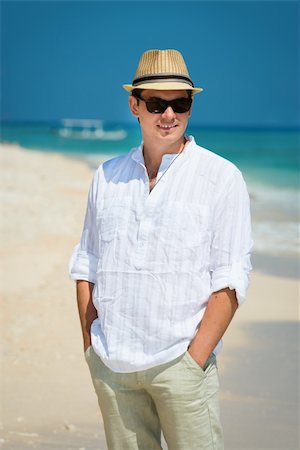 Carefree happy young man in sunglasses and hat on the sunny coast with the blue sea and boat on background Stock Photo - Budget Royalty-Free & Subscription, Code: 400-06455935