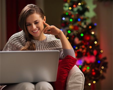 Happy woman looking in laptop in front of Christmas tree Stock Photo - Budget Royalty-Free & Subscription, Code: 400-06458801