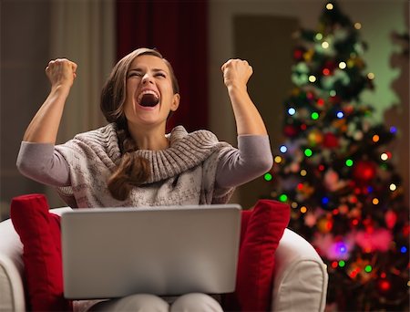Happy woman with laptop rejoicing success in front of Christmas tree Stock Photo - Budget Royalty-Free & Subscription, Code: 400-06458802