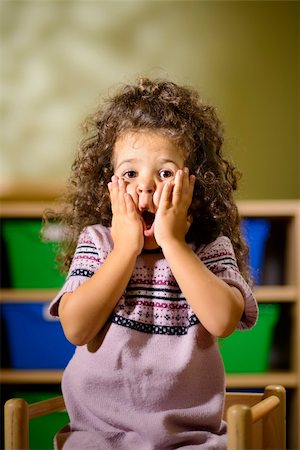 Portraits of children, 3 years old female with curly hair looking at camera in kindergarten with worried expression Stock Photo - Budget Royalty-Free & Subscription, Code: 400-06459859