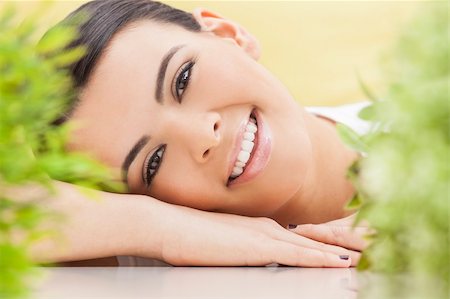 simsearch:400-05733700,k - Health spa nature concept studio portrait of a beautiful young woman or girl resting on her hands smiling through natural green leaves Photographie de stock - Aubaine LD & Abonnement, Code: 400-06461311