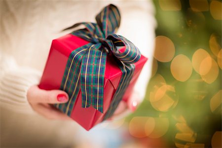 simsearch:400-06462603,k - Woman Wearing A Sweater and Seasonal Red Mittens Against an Abstract Green and Golden Background Holding A Beautifully Wrapped Christmas Gift with Narrow Depth of Field. Stock Photo - Budget Royalty-Free & Subscription, Code: 400-06462607