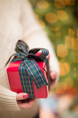 simsearch:400-06462603,k - Woman Wearing A Sweater and Seasonal Red Mittens Against an Abstract Green and Golden Background Holding A Beautifully Wrapped Christmas Gift with Narrow Depth of Field. Stock Photo - Budget Royalty-Free & Subscription, Code: 400-06462608