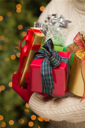 simsearch:400-06462603,k - Woman Wearing A Sweater and Seasonal Red Mittens Against an Abstract Green and Golden Background Holding Beautifully Wrapped Christmas Gifts. Stock Photo - Budget Royalty-Free & Subscription, Code: 400-06462612