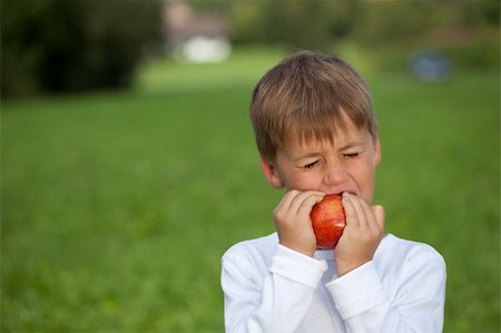simsearch:400-04979626,k - Child eats an apple on a meadow. Shallow depth of field. Foto de stock - Super Valor sin royalties y Suscripción, Código: 400-06463473