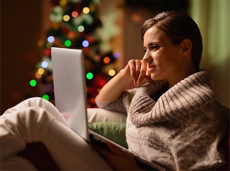 Young woman sitting chair with laptop in front of Christmas tree Stock Photo - Budget Royalty-Free & Subscription, Code: 400-06463602