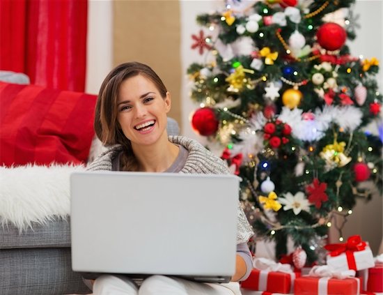 Smiling young woman with laptop sitting near Christmas tree Stock Photo - Royalty-Free, Artist: citalliance, Image code: 400-06463695