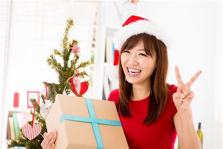 simsearch:400-06477682,k - Excited Asian woman getting her Christmas present, showing peace hand sign, indoor/inside her home. Stock Photo - Budget Royalty-Free & Subscription, Code: 400-06477673