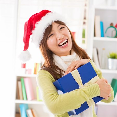 simsearch:400-06477682,k - Asian female holding her Christmas gift smiling happily, indoor/inside house. Stock Photo - Budget Royalty-Free & Subscription, Code: 400-06477684