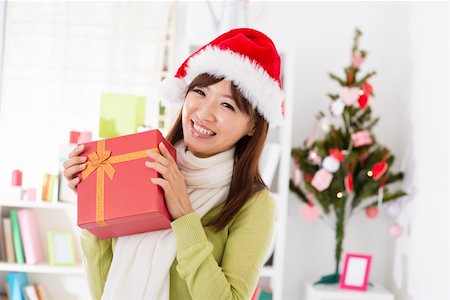 simsearch:400-06477682,k - Happy Asian woman in santa hat showing her Christmas gift Stock Photo - Budget Royalty-Free & Subscription, Code: 400-06477683