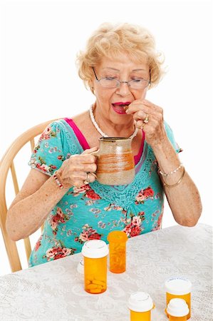pillbox - Healthy senior woman taking her daily doses of medicine.  White background. Stock Photo - Budget Royalty-Free & Subscription, Code: 400-06478843