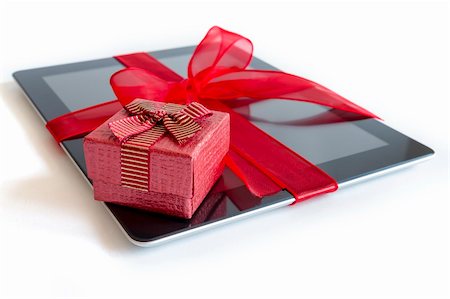 Digital tablet with red ribbon gift isolated on white. Foto de stock - Super Valor sin royalties y Suscripción, Código: 400-06472841