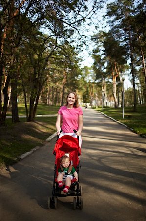 simsearch:400-06452404,k - Young smiling mother with her 1 year son in the buggy walking outdoors in the park. Springday, natural colors, shallow dof (prime 35mm L optics) Photographie de stock - Aubaine LD & Abonnement, Code: 400-06481372