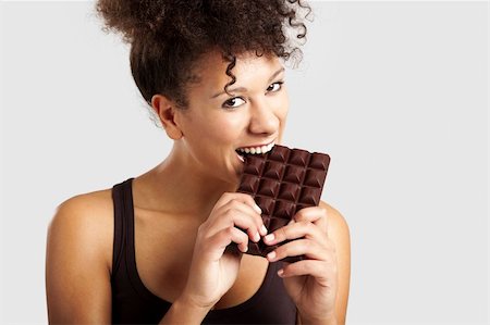 Beautiful african woman holding and eating a huge dark chocolate bar Stock Photo - Budget Royalty-Free & Subscription, Code: 400-06481593