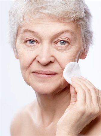 simsearch:400-06482471,k - Elderly woman wipes the skin on a white background Stock Photo - Budget Royalty-Free & Subscription, Code: 400-06482468