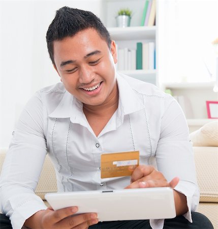 Southeast Asian man online shopping, hands holding credit card and computer tab sitting at home. Stock Photo - Budget Royalty-Free & Subscription, Code: 400-06483298