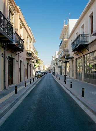 rethymno - Driving through the city street stretches away to the horizon. Along it are town houses and shops. Stockbilder - Microstock & Abonnement, Bildnummer: 400-06483402