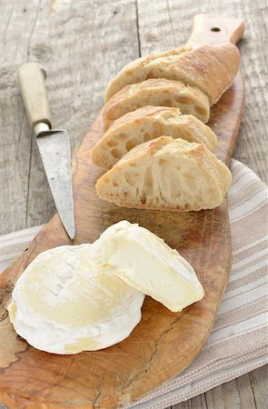 French St Marcellin soft cheese on a rustic board with sliced french baguette and an old knife Photographie de stock - Aubaine LD & Abonnement, Code: 400-06517491