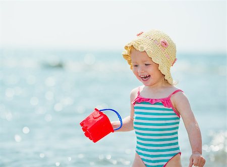 Smiling baby playing with pail on seashore Photographie de stock - Aubaine LD & Abonnement, Code: 400-06525222