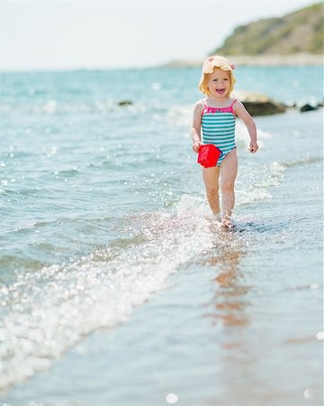 Happy baby with pail running along seashore Photographie de stock - Aubaine LD & Abonnement, Code: 400-06525223