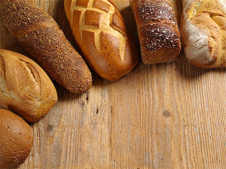 Photo of loaves of uncut bread resting on an old wood table. Stock Photo - Budget Royalty-Free & Subscription, Code: 400-06525441