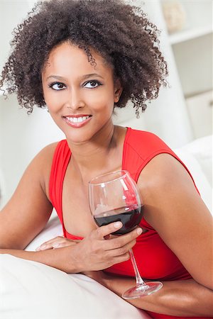 A beautiful happy mixed race African American girl or young woman wearing a red dress and drinking red wine at home Stock Photo - Budget Royalty-Free & Subscription, Code: 400-06525459