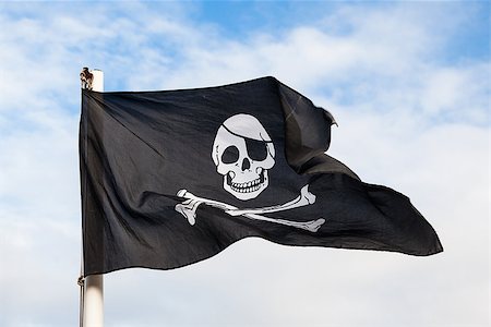 pirate dead - Waving Pirate flag isolated on blue sky Photographie de stock - Aubaine LD & Abonnement, Code: 400-06525746