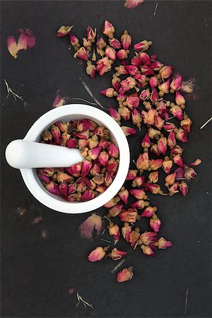simsearch:400-07175956,k - Rosebud flower heads in a white mortar with pestle over rose impregnated black paper, used in chinese herbal medicine. Stock Photo - Budget Royalty-Free & Subscription, Code: 400-06527888
