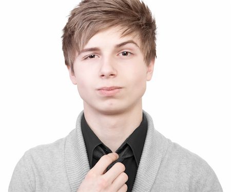 A young man in a gray cardigan straightens his tie Stock Photo - Budget Royalty-Free & Subscription, Code: 400-06520692