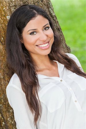 simsearch:400-07112758,k - Outdoor portrait of a beautiful young Latina Hispanic woman smiling leaning against a tree Fotografie stock - Microstock e Abbonamento, Codice: 400-06521639