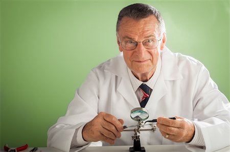 An older male wearing a white lab coat and repairing electronic equipments, like a technician or a repair man. Stock Photo - Budget Royalty-Free & Subscription, Code: 400-06554374