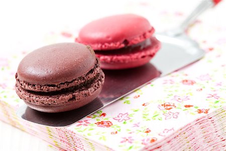 simsearch:400-06564979,k - Close-up of two colorful macaroons on serviette and cake server on light background Stock Photo - Budget Royalty-Free & Subscription, Code: 400-06556504