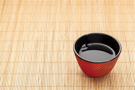 emaille - Japanese cup of tea on a bamboo mat - a traditional cast iron red hobnail design with black enamel inside Stockbilder - Microstock & Abonnement, Bildnummer: 400-06558596