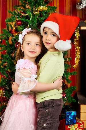 sister hugs baby - two beautiful child stand near christmas tree Photographie de stock - Aubaine LD & Abonnement, Code: 400-06558847