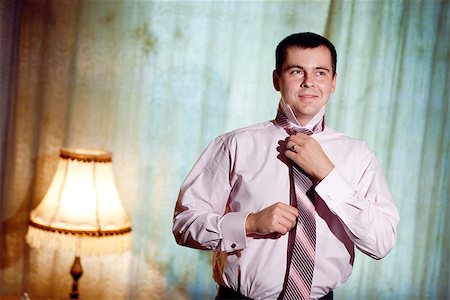 putting on tie - portrait of a young man putting on a necktie Stock Photo - Budget Royalty-Free & Subscription, Code: 400-06559749
